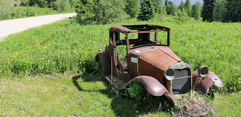 an old rusty car in a field of grass