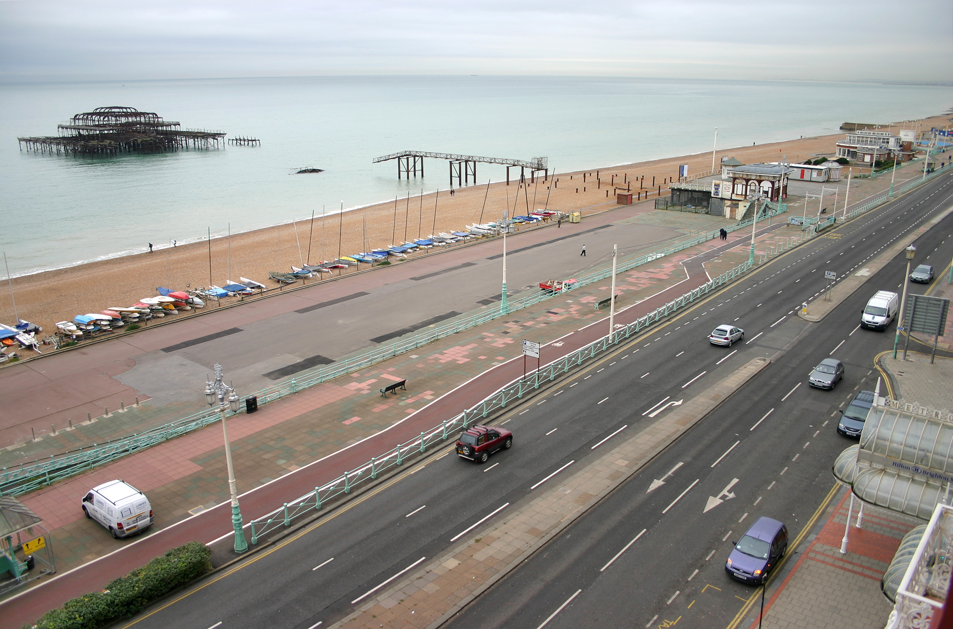 a road with cars on it and a beach with a pier