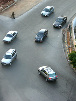 cars on a road with a person standing on the corner