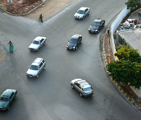 cars on a road with a person standing on the corner