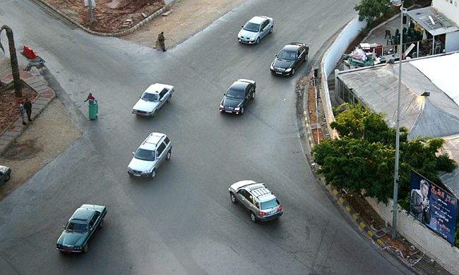 cars on a road with a person standing on the corner