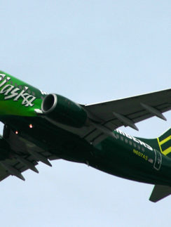 a green and white airplane flying in the sky