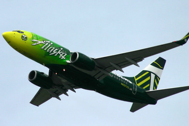 a green and white airplane flying in the sky