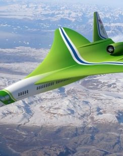a green airplane flying over mountains