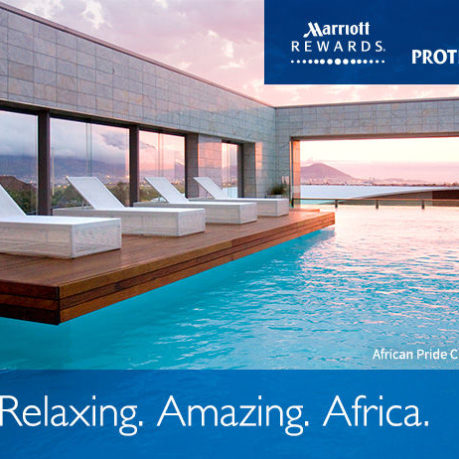 a pool with lounge chairs and a building with a sunset