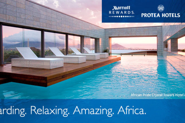 a pool with lounge chairs and a building with a sunset