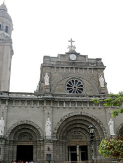 a stone building with a clock tower with Manila Cathedral in the background