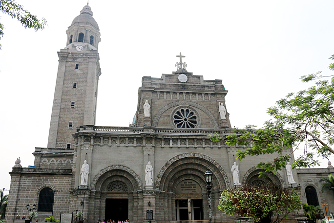 a stone building with a clock tower with Manila Cathedral in the background