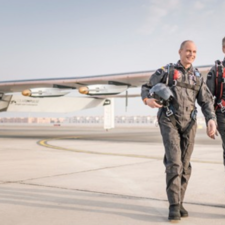 two men in flight gear walking on a runway