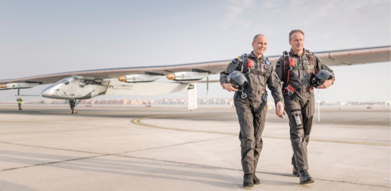 two men in flight gear walking on a runway