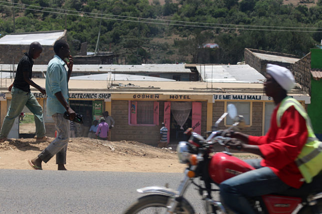 a man walking on a road with a red motorcycle and a red motorcycle