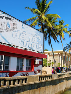 a building with palm trees and people walking on the side of the road