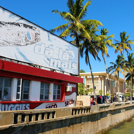 a building with palm trees and people walking on the side of the road