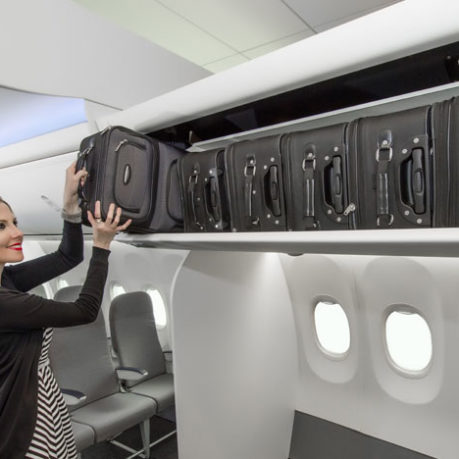 a woman putting luggage on a shelf