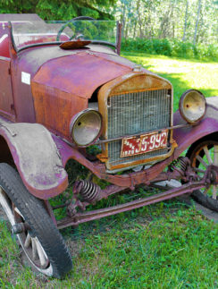 an old rusty car parked in a grassy area