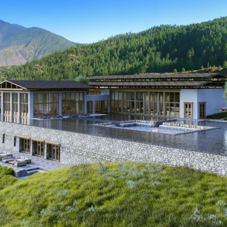 a building with a pool and a grassy hill