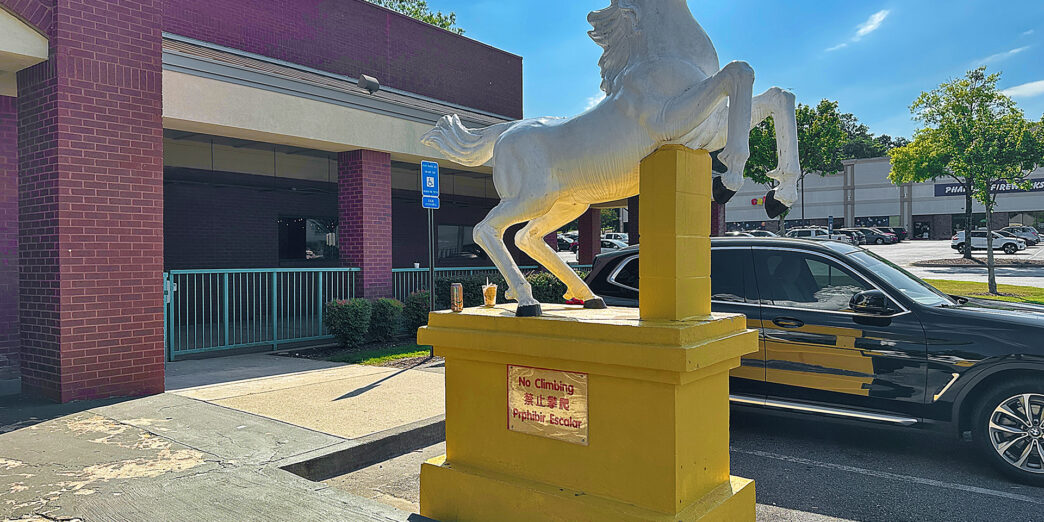 a white horse statue on a yellow pedestal