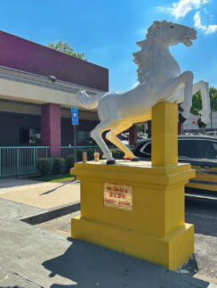 a white horse statue on a yellow pedestal