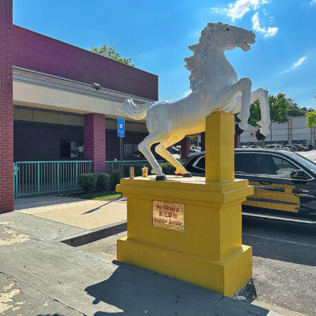 a white horse statue on a yellow pedestal