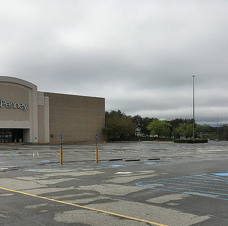 a large parking lot with a building and trees in the background