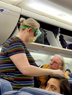 a woman in a striped shirt and mask standing in an airplane