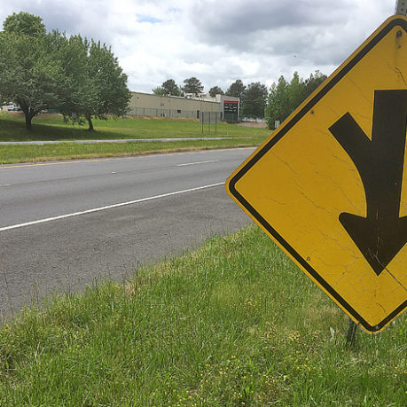 a yellow sign on a pole next to a road