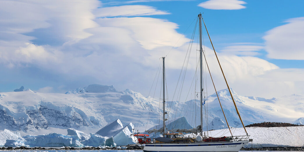 a sailboat in the water with snow covered mountains in the background