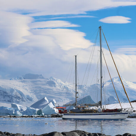 a sailboat in the water with snow covered mountains in the background