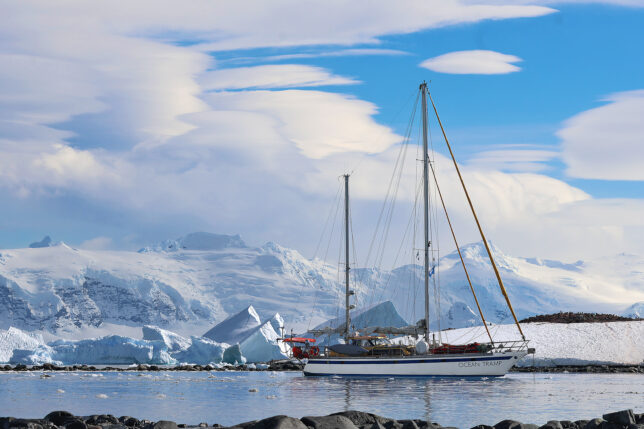 a sailboat in the water with snow covered mountains in the background