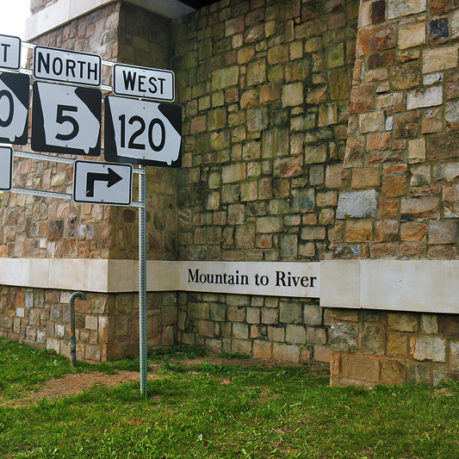 a sign next to a stone wall