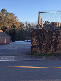 a fenced in area with a building and trees in the background