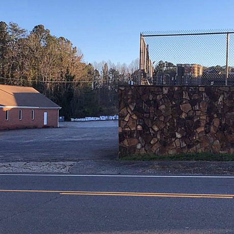 a fenced in area with a building and trees in the background