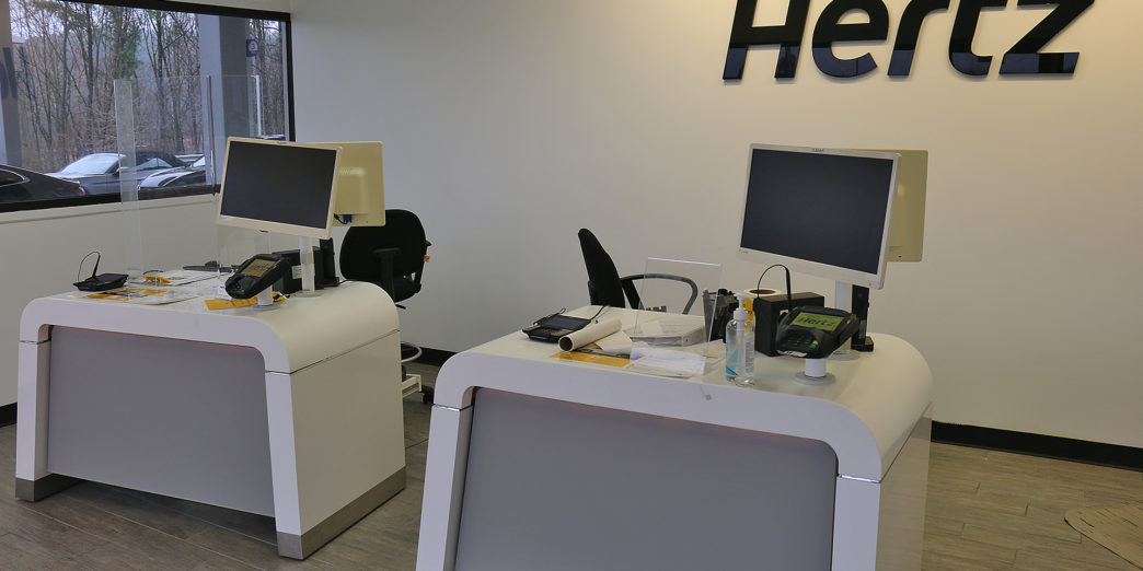 a two white desks with computers and a black sign on the wall