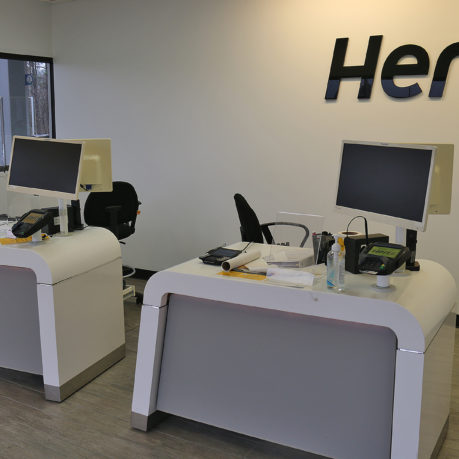 a two white desks with computers and a black sign on the wall