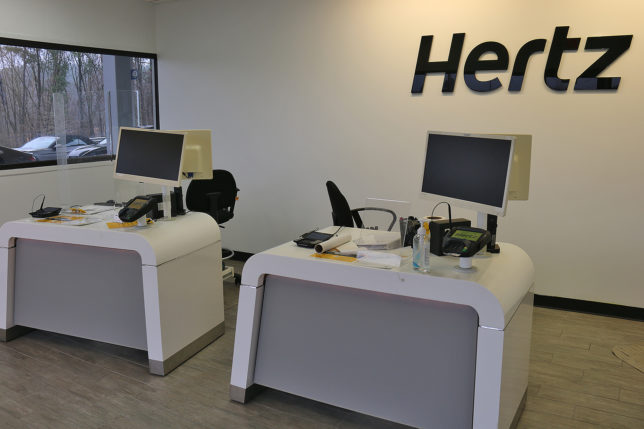 a two white desks with computers and a black sign on the wall