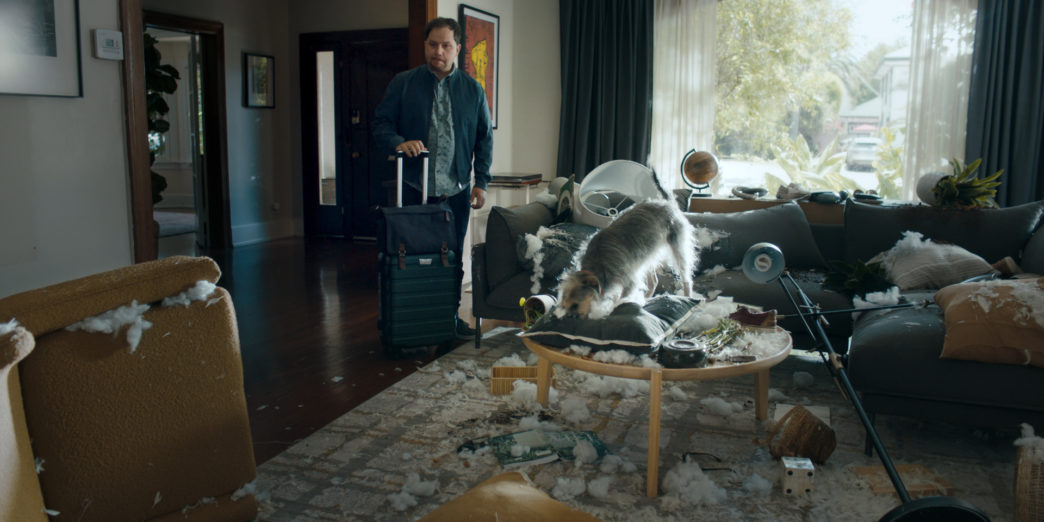 a man standing in a room with a dog on a coffee table