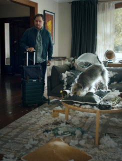 a man standing in a room with a dog on a coffee table