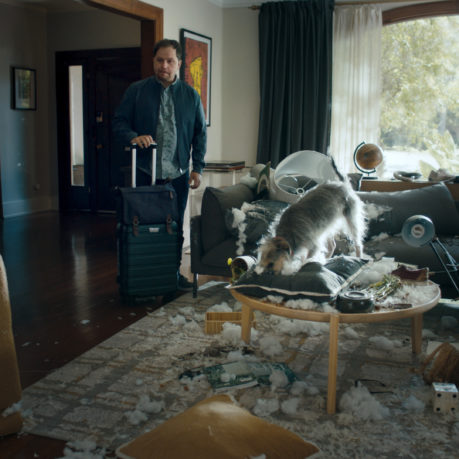 a man standing in a room with a dog on a coffee table
