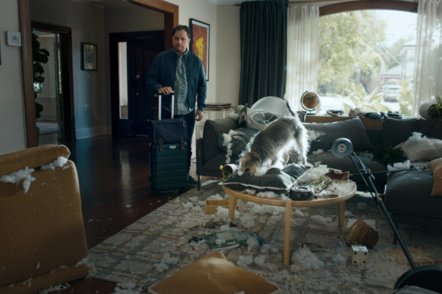 a man standing in a room with a dog on a coffee table