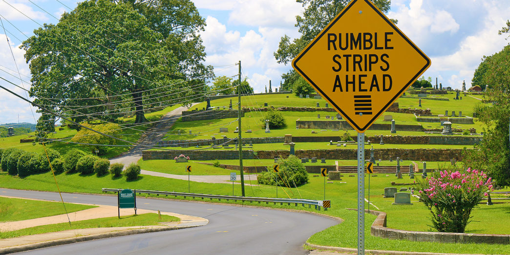 a road sign with grass and trees