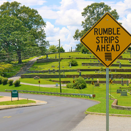 a road sign with grass and trees