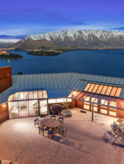 a building with a glass roof and a lake and mountains in the background