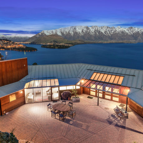 a building with a glass roof and a lake and mountains in the background