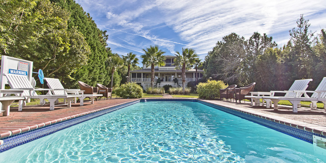 a pool with chairs and a house in the background