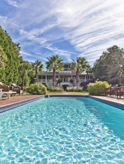 a pool with chairs and a house in the background
