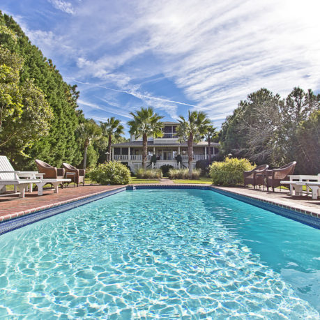 a pool with chairs and a house in the background
