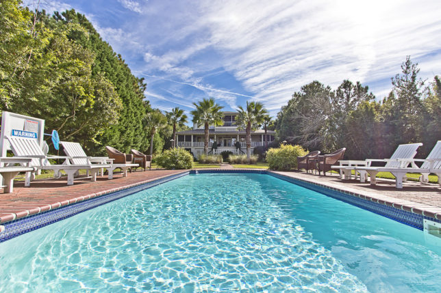 a pool with chairs and a house in the background