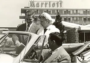 a group of people in suits standing in front of a car