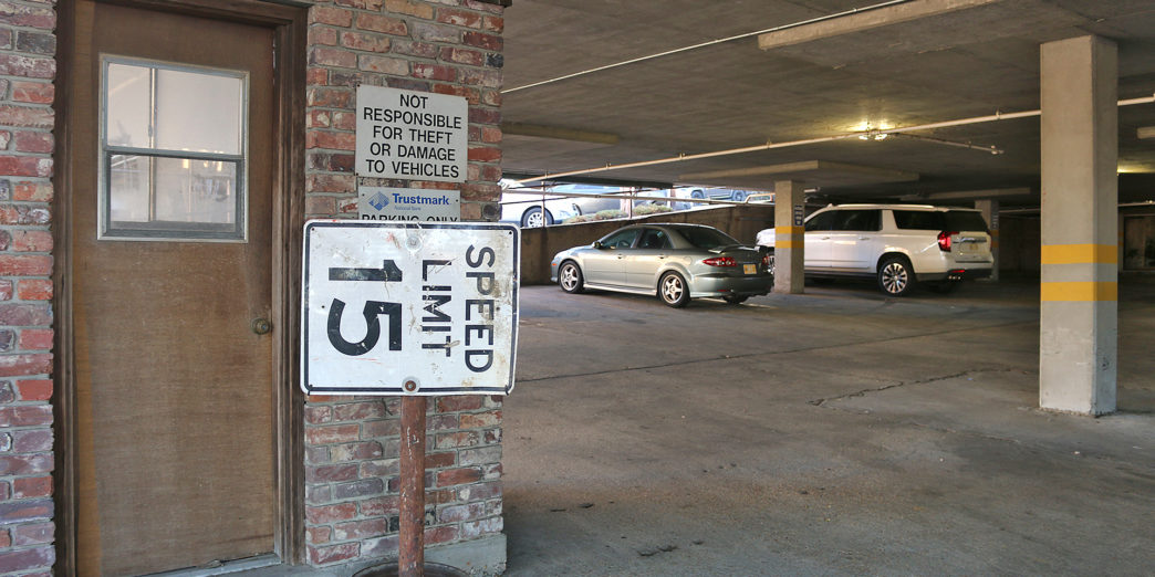 a parking garage with a sign and cars in the background