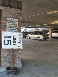 a parking garage with a sign and cars in the background